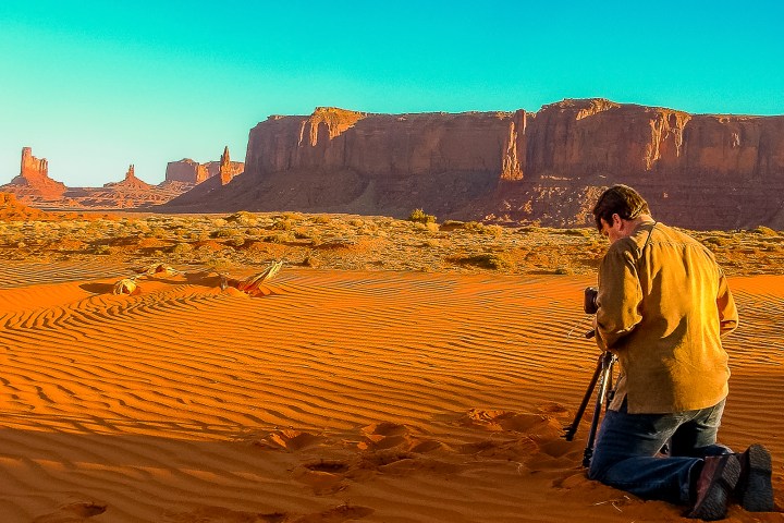 a man standing in front of a sunset at first stop in monument valley