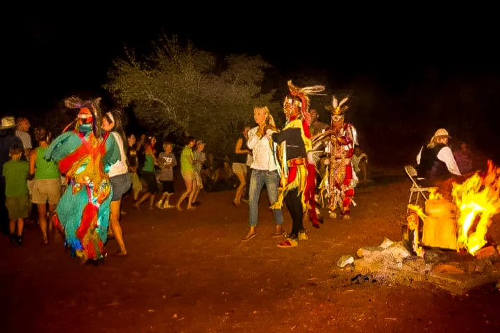 a group of people dancing by the campfire