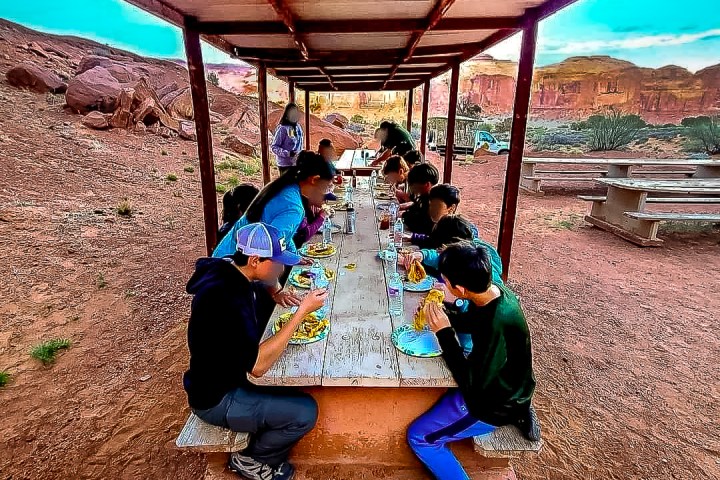 a group of people eating dinner at a picnic table
